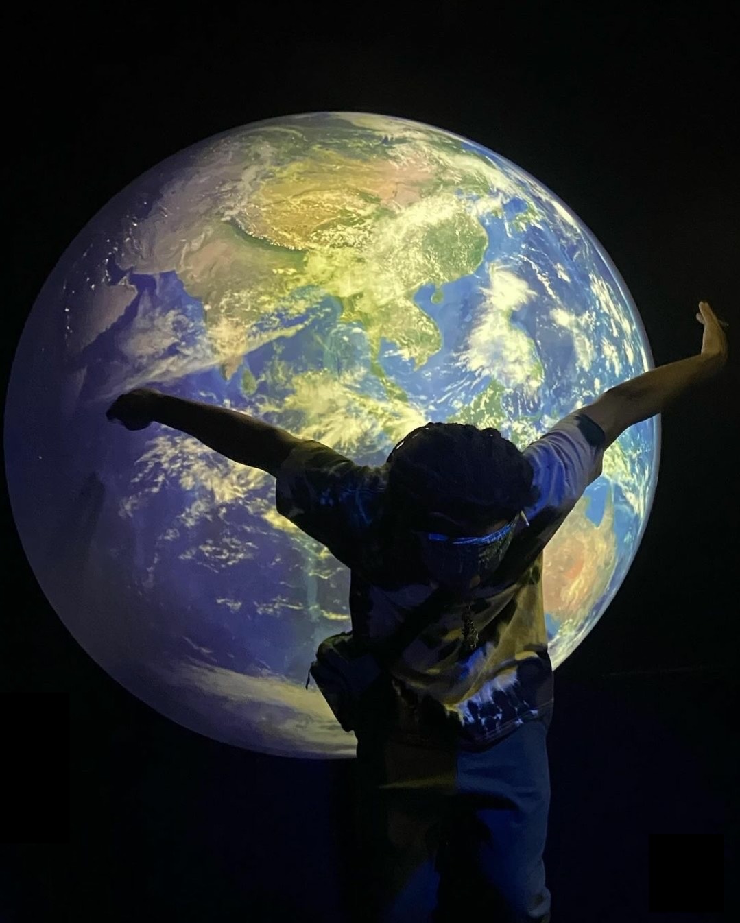 Wyrmstar landing a dance jump in front of a large glowing globe.